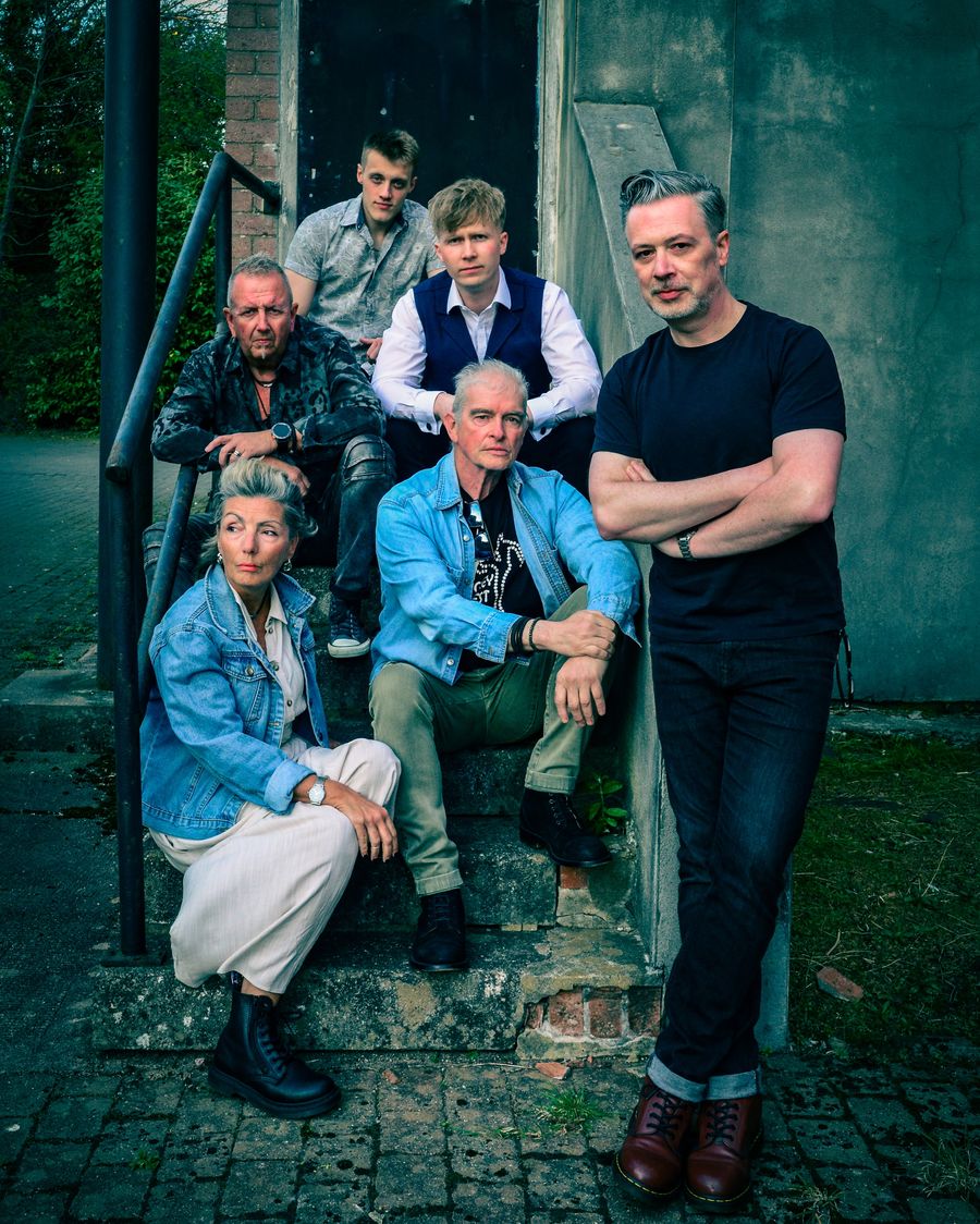 The band photographed together on a stone stairway